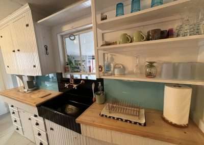 Vintage sink, essential glassware, and the smallest dish drying rack you’ll ever see. Note that the sink is separate from the refrigerator and cooking area, which are in the back room.