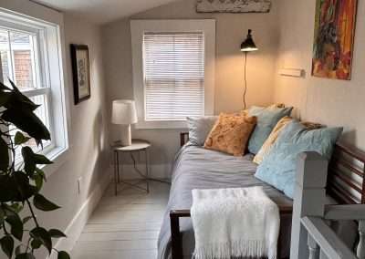 Porch has kitchenette and a daybed. View out the back is of trees, wetlands, lots of birds